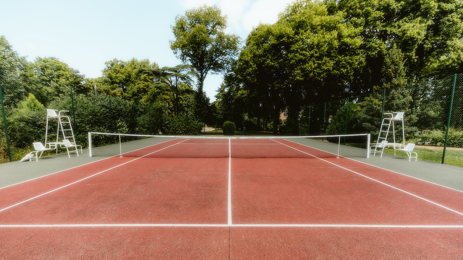 A tennis court with two chairs and a tennis racket